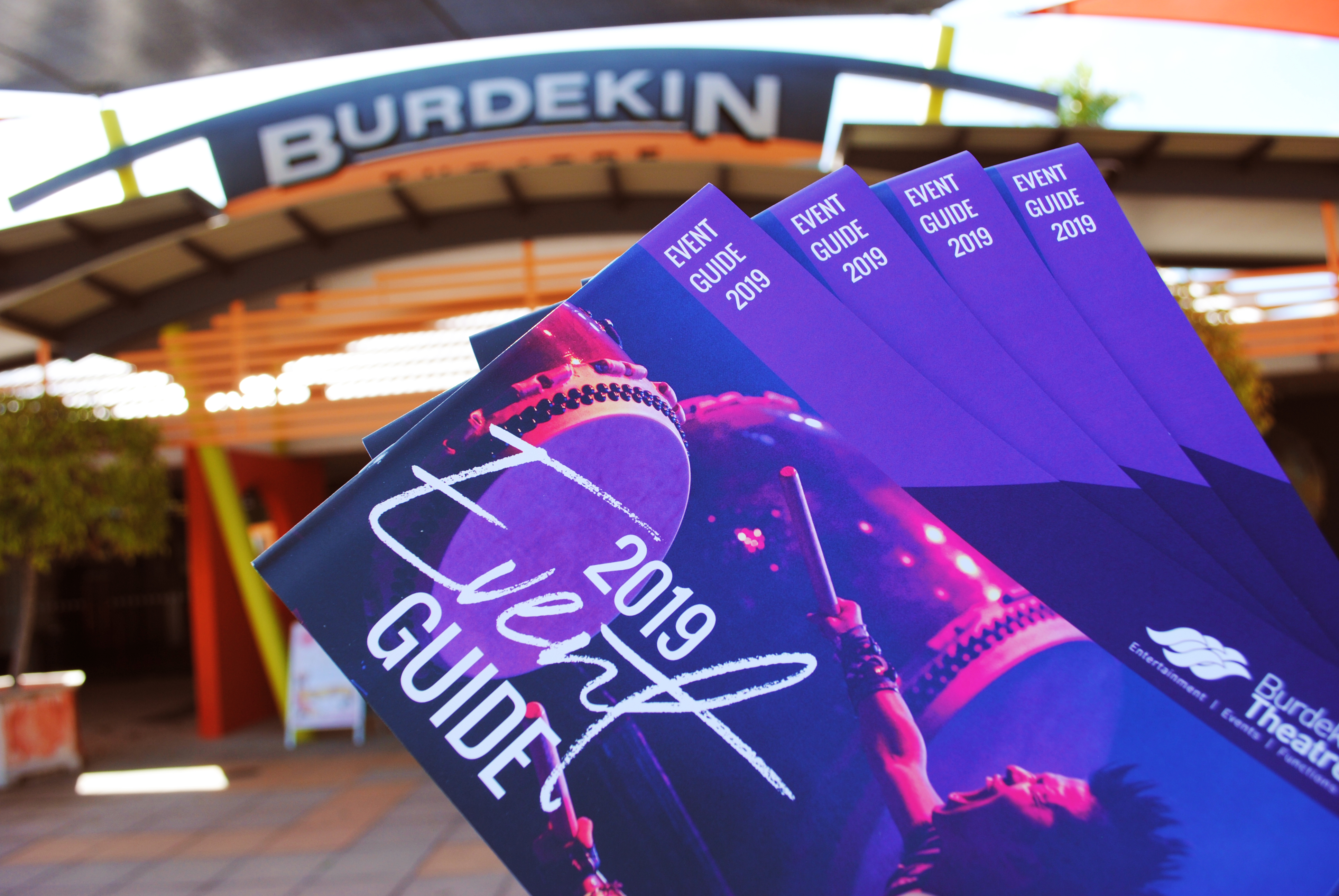 Purple booklets being held up in front of Burdekin Theatre front signage
